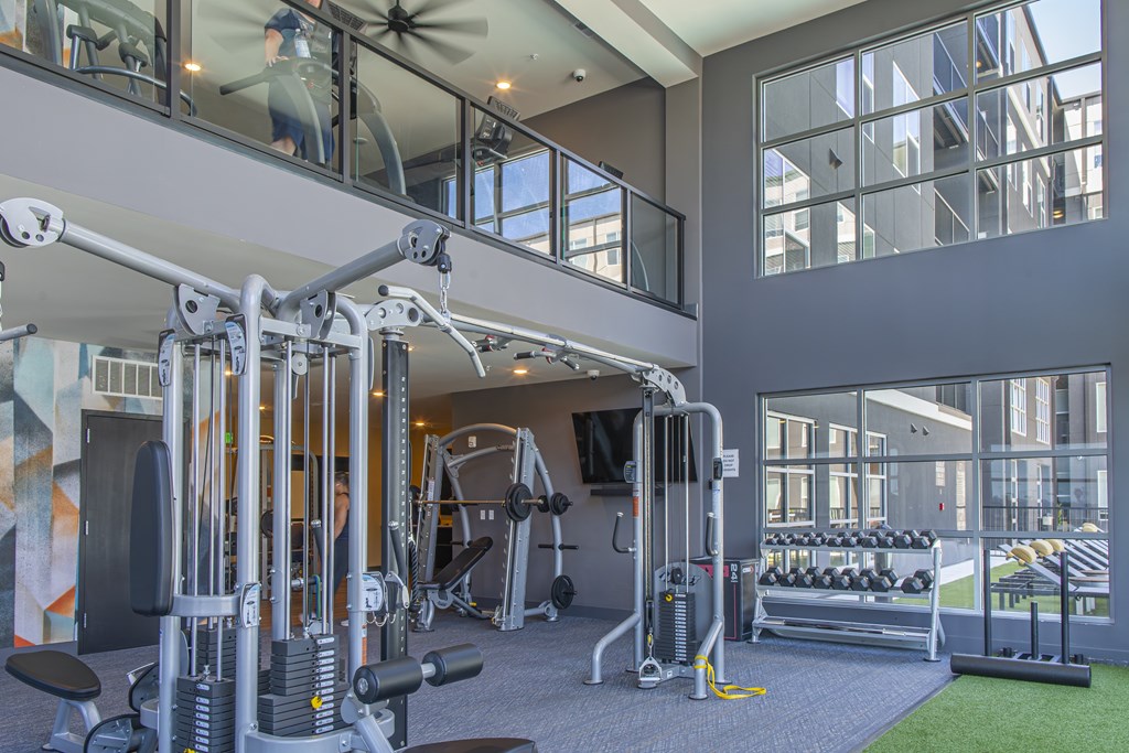A gym with a variety of equipment including a weight bench, a leg press machine, and a treadmill.