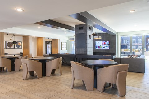 A modern dining room with a black table surrounded by tan chairs.