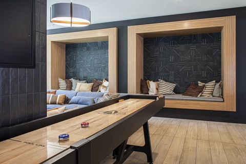 A shiny pool table is in the middle of a room with a couch and a lamp.