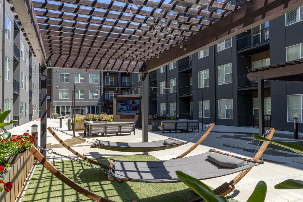 A patio with a hammock and a table surrounded by buildings.