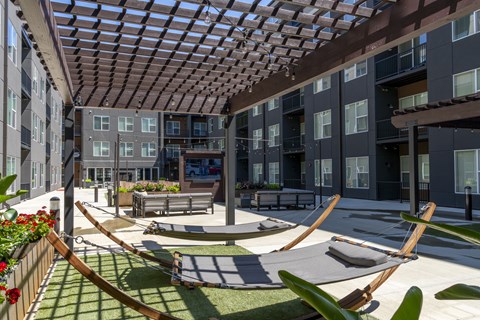 A patio with a hammock and a table surrounded by buildings.