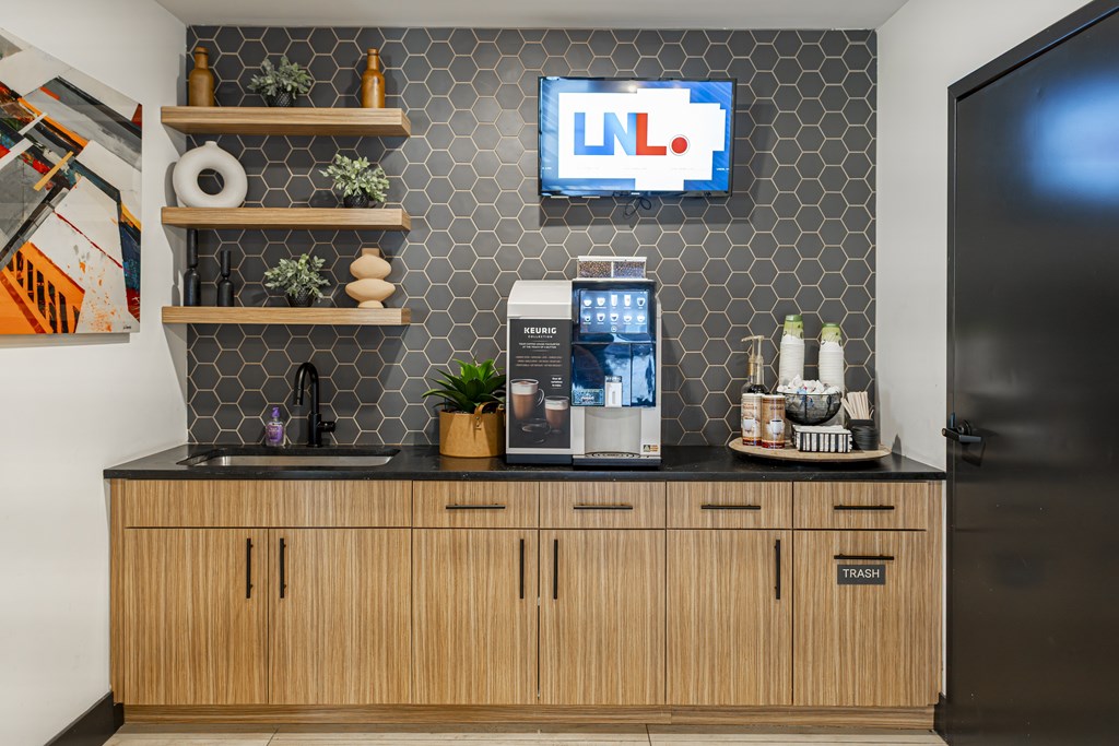 A kitchen with wooden cabinets and a counter with a coffee machine and a plant on it.