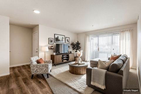 A living room with a grey couch, a wooden coffee table, and a chair with a patterned cushion.