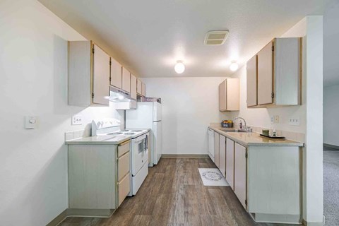 A kitchen with white appliances and wooden floors.