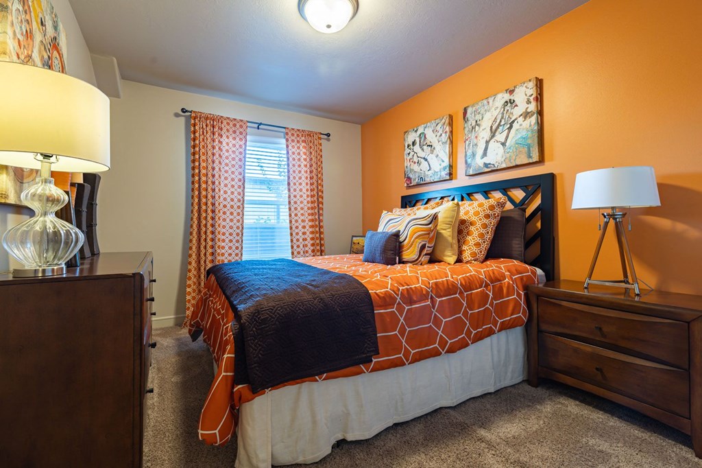 bedroom with orange walls and a bed with orange and white comforter