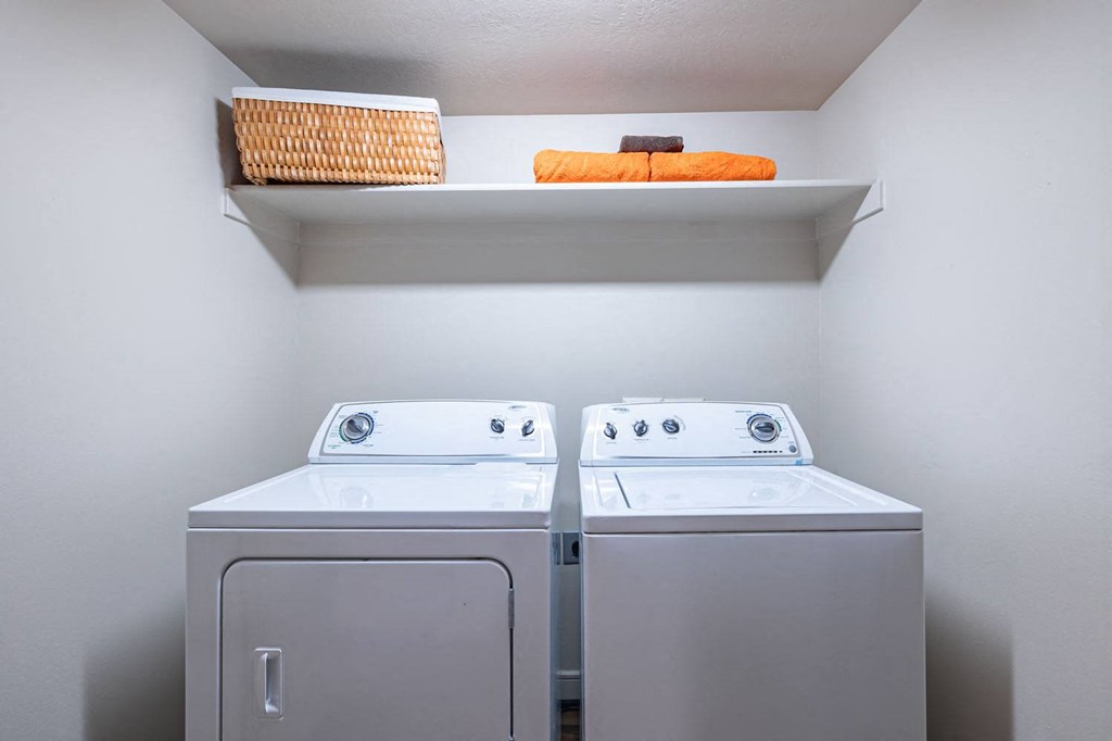 a washer and dryer in a laundry room with a shelf above them