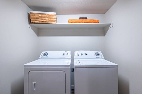 a washer and dryer in a laundry room with a shelf above them