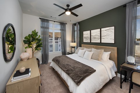 Bedroom with bed, accent wall, dresser, ceiling fan, and nightstands