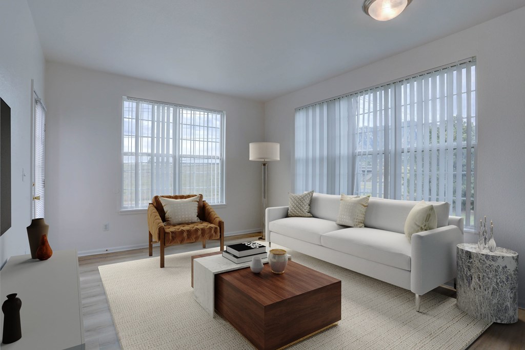 A living room with a white couch, a wooden coffee table, and a window with white curtains.