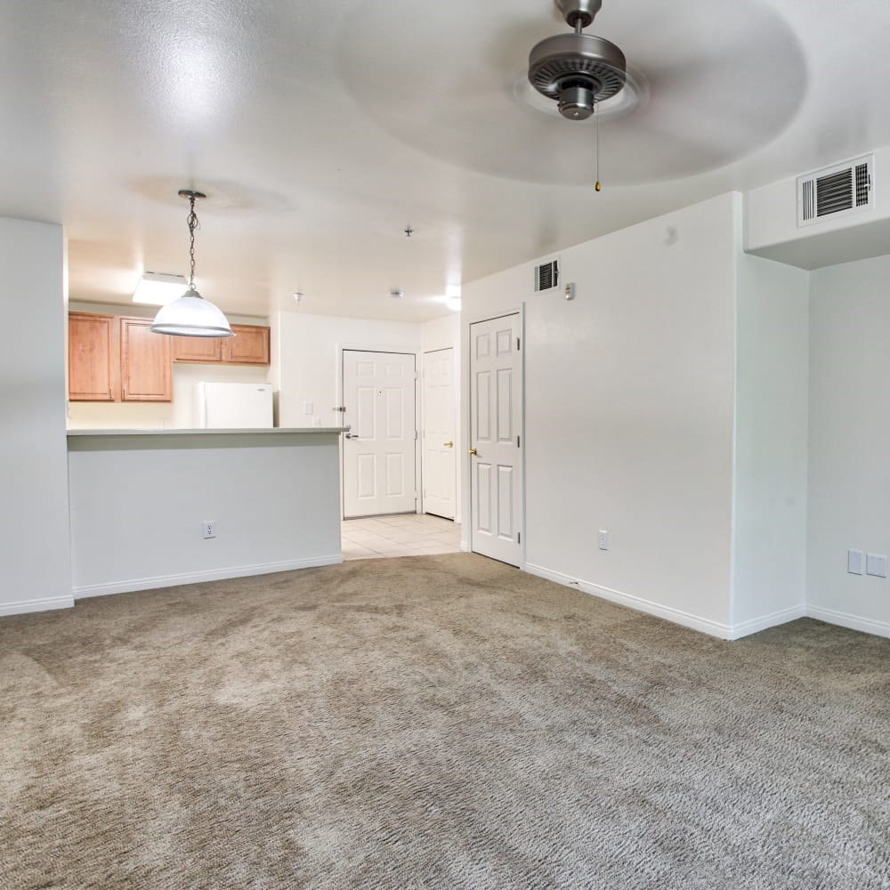 an empty living room and kitchen with a ceiling fan
