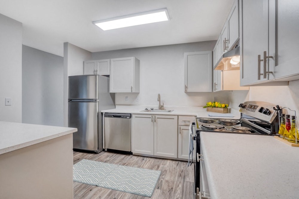 a white kitchen with stainless steel appliances and white counter tops