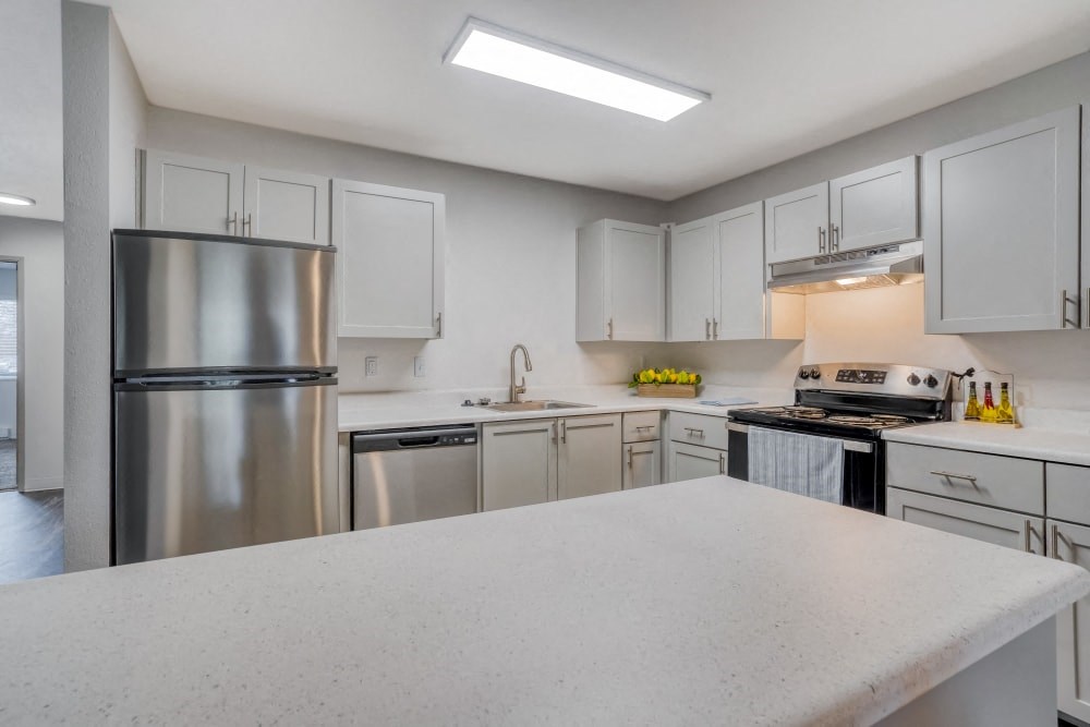 a white kitchen with stainless steel appliances and white counter tops
