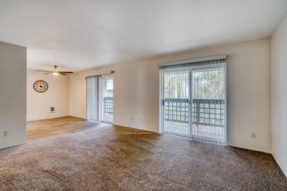 an empty living room with a sliding glass door to a balcony