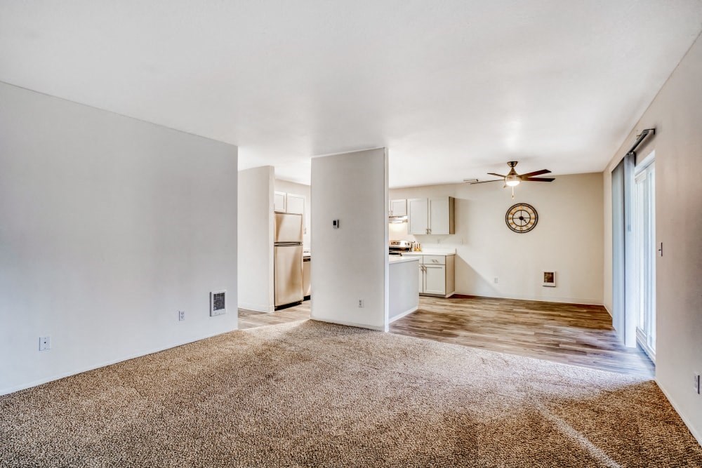 an empty living room and kitchen with a ceiling fan