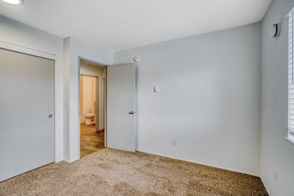 a bedroom with white walls and a door to a bathroom