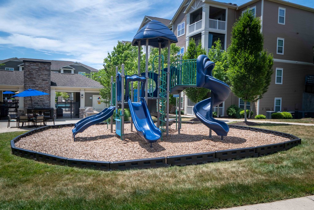 a playground with slides in front of an apartment building