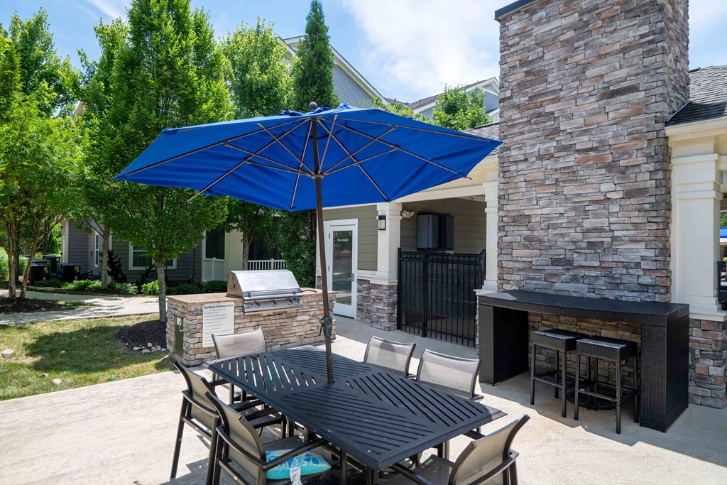 a patio with a blue umbrella and a table with chairs