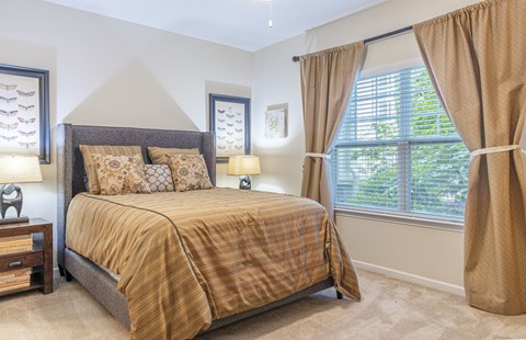 A bedroom with a bed, nightstand, and window.