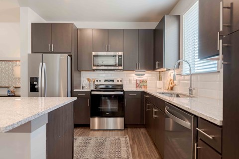 A modern kitchen with stainless steel appliances and wooden flooring.