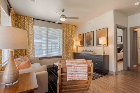 A living room with a white couch, a wooden chair, and a lamp.