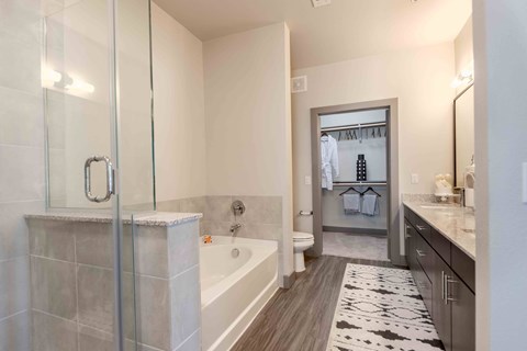 A bathroom with a glass shower door and a bathtub.