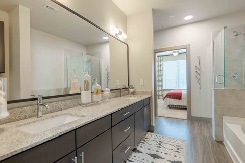 A bathroom with a large mirror, a sink, and a shower.