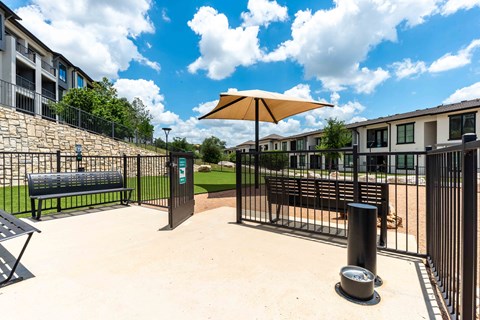 A sunny day at the park with a yellow umbrella and a bench.