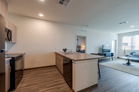 A kitchen with a refrigerator, dishwasher, and a countertop with a sink.