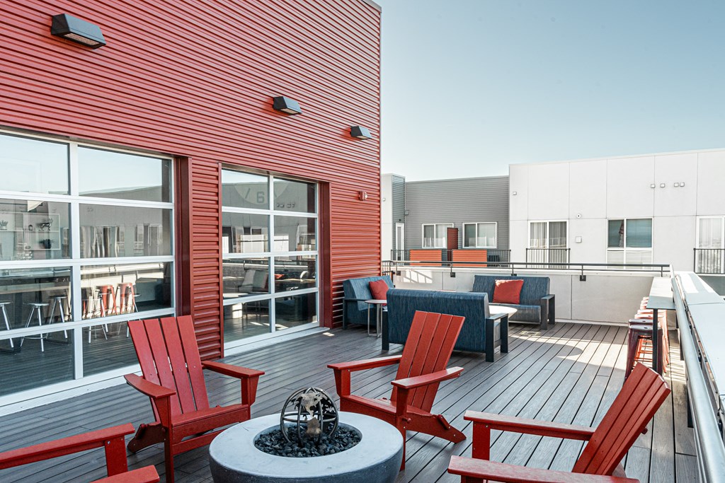 a large deck with red chairs and a fire pit