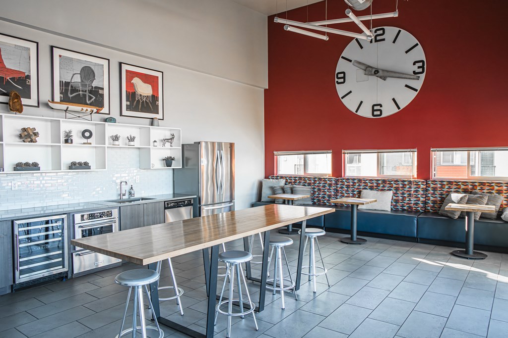 a lounge with a large clock on the wall and a table with stools