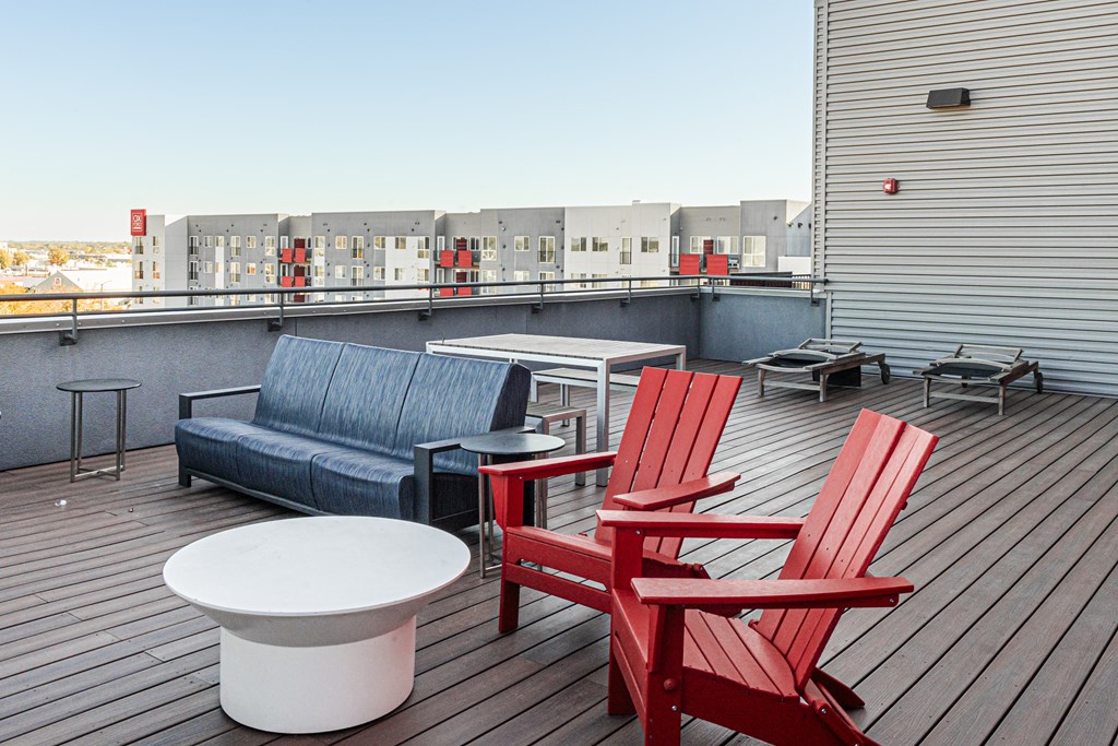 a rooftop deck with two red chairs and a blue couch