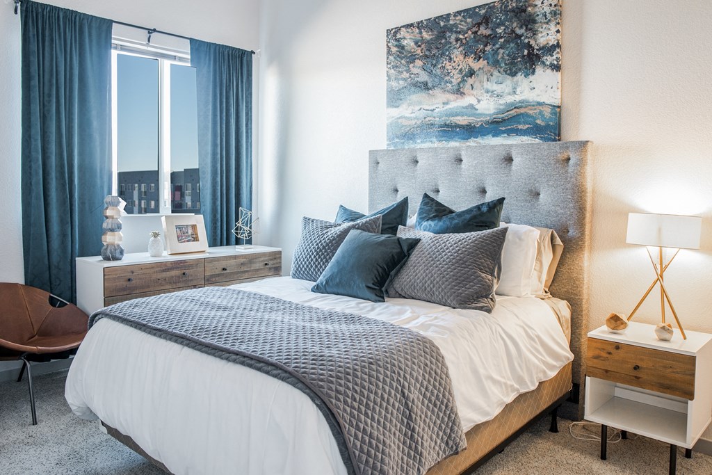 a bedroom with a bed with blue and white pillows and a large window