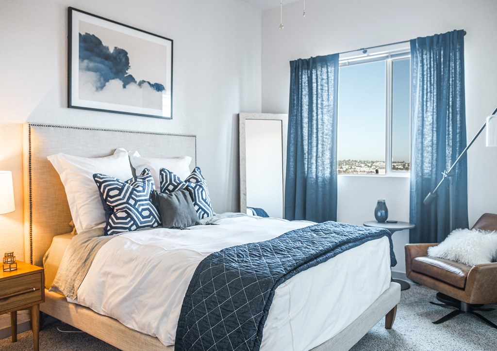 a bedroom with a large bed and a window with blue curtains