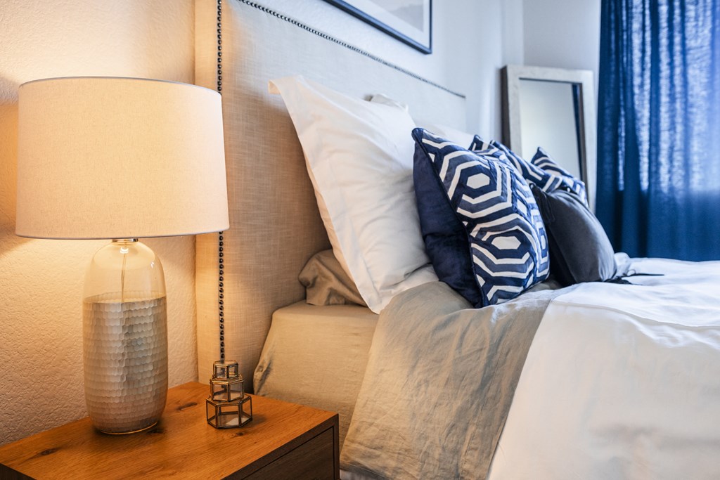 a bedroom with a bed with pillows and a nightstand with a lamp