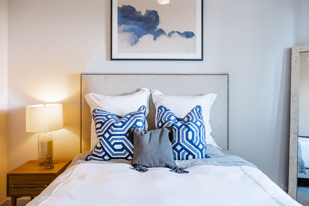 a bedroom with a bed with blue and white pillows and atainedtained window