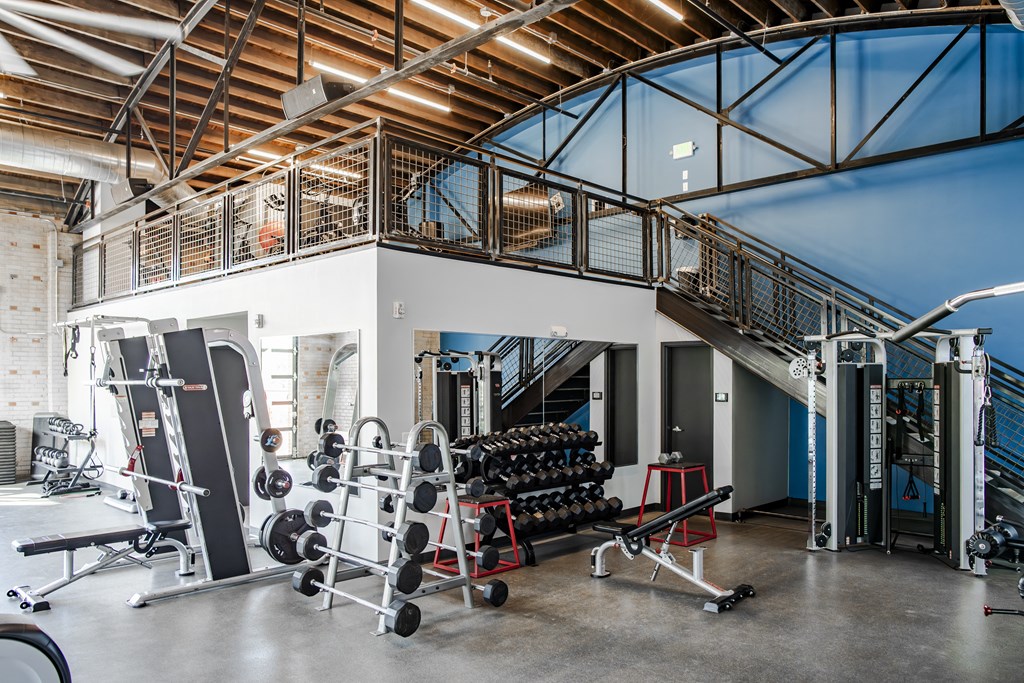a gym with weights and cardio equipment and a spiral staircase