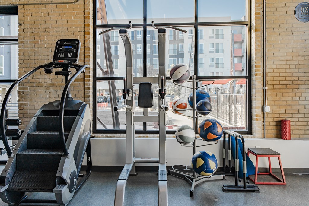 a gym with a treadmill and weights next to a window