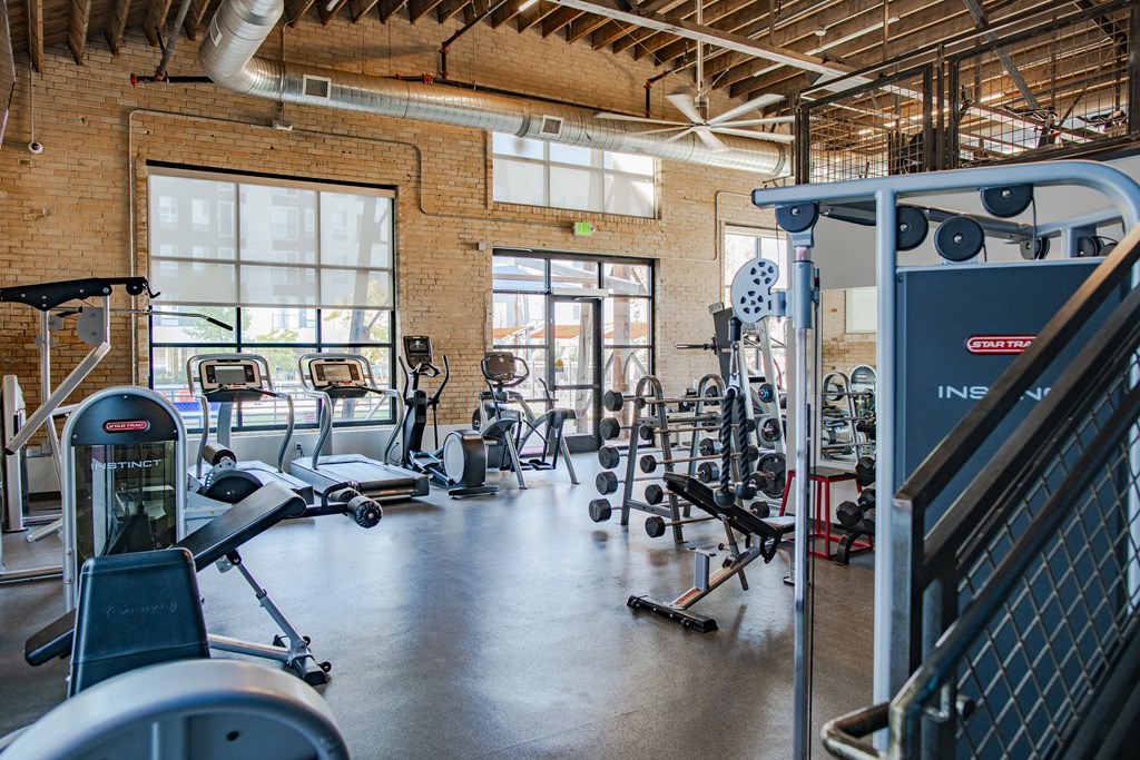 a gym with weights and cardio equipment in a building with windows