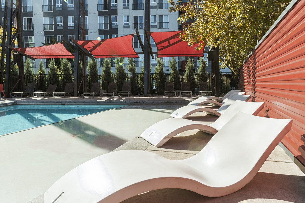 a group of white lounge chairs next to a swimming pool