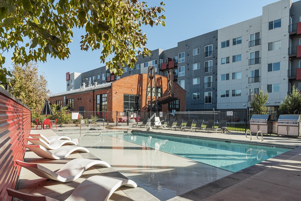 an outdoor pool with lounge chairs and a building in the background