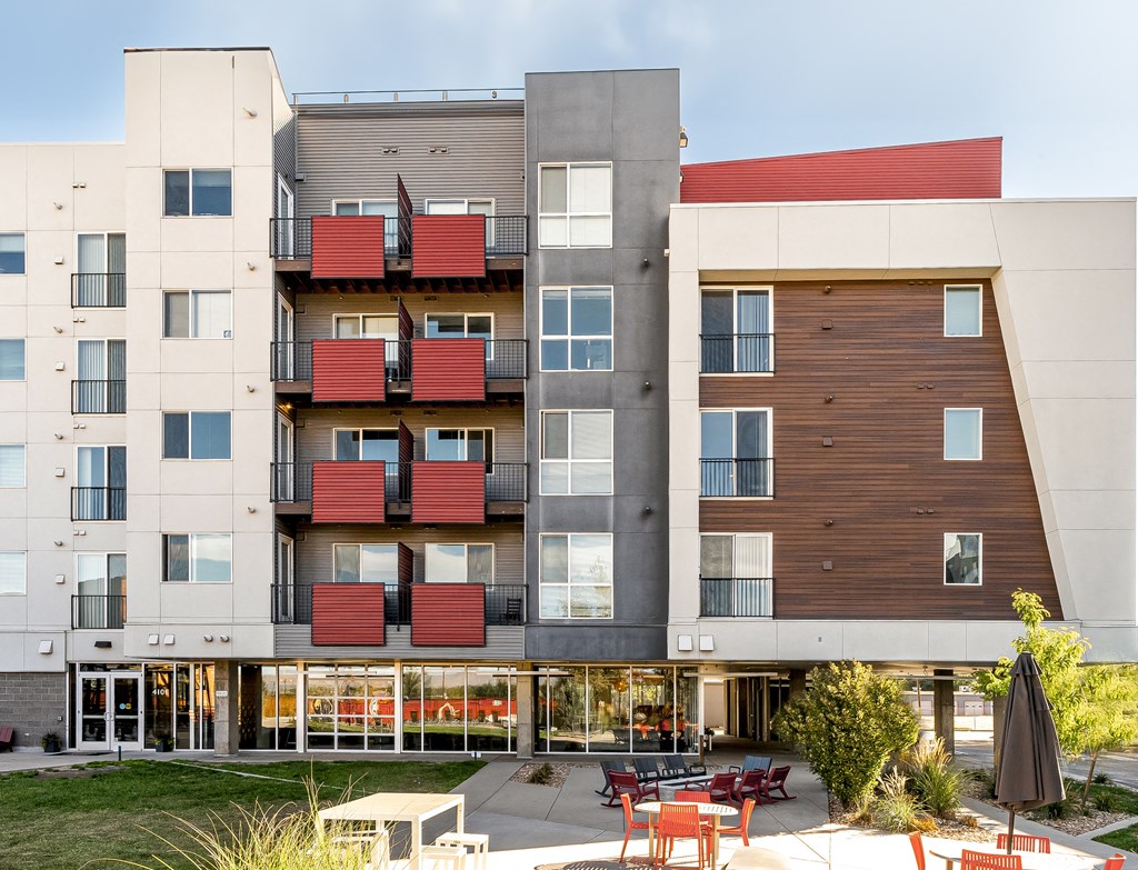 an exterior view of an apartment building with tables and chairs