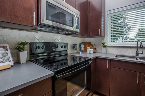 A modern kitchen with dark wood cabinets and a black stove top oven.