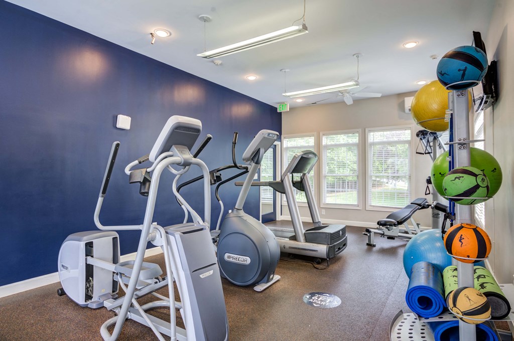 a gym with cardio equipment and weights on the wall