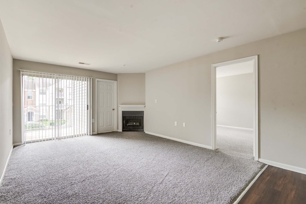 a living room with white walls and a door to a balcony