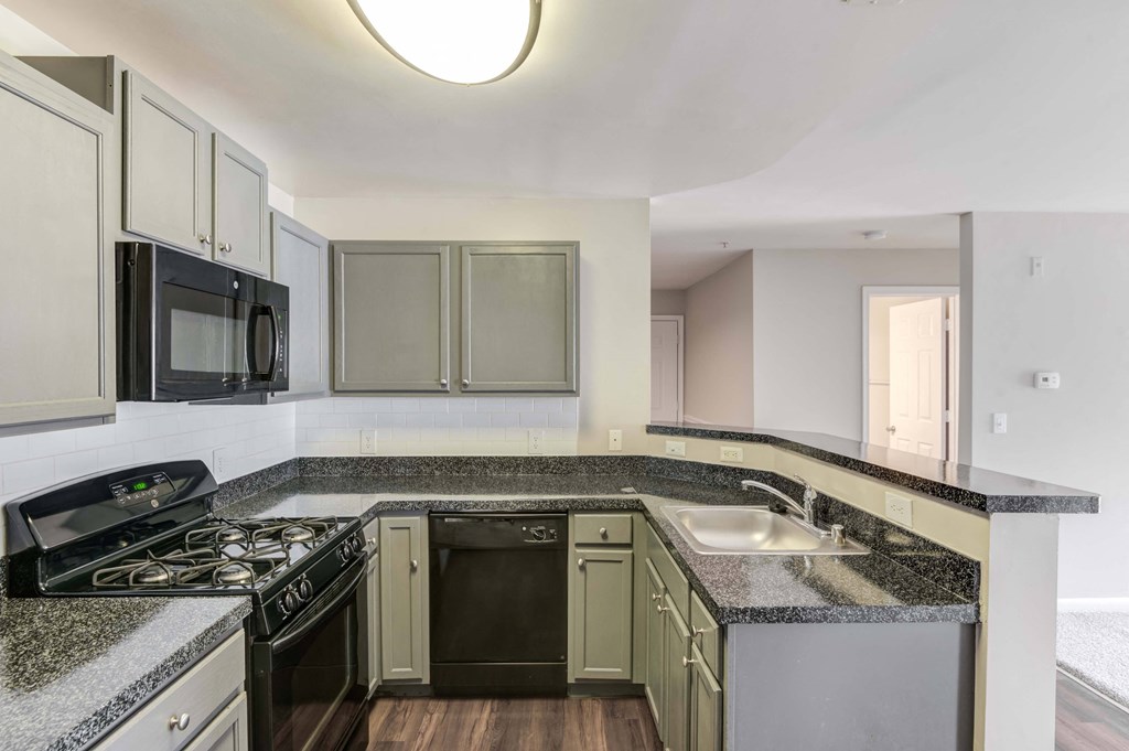an empty kitchen with granite counter tops and black appliances