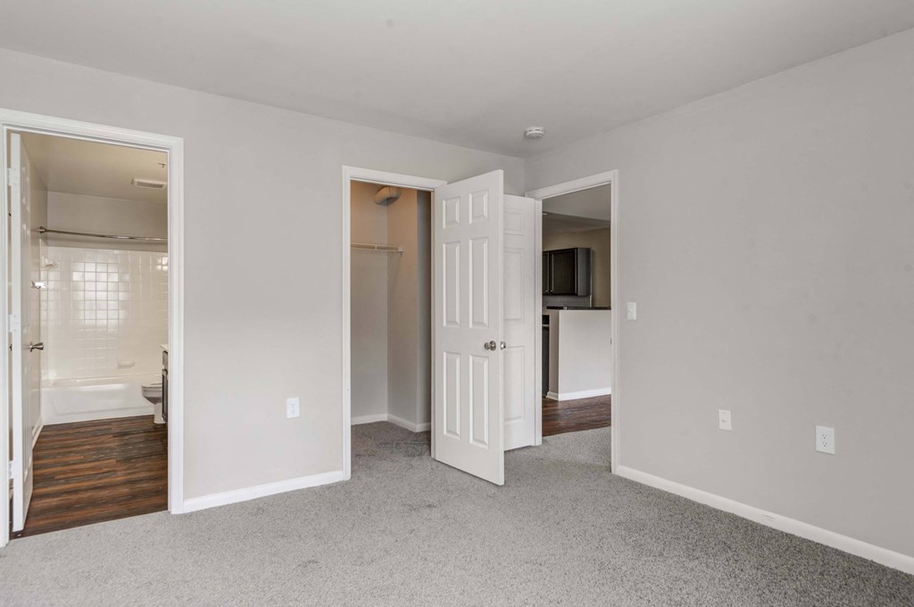 a bedroom with an open door to a bathroom and a kitchen