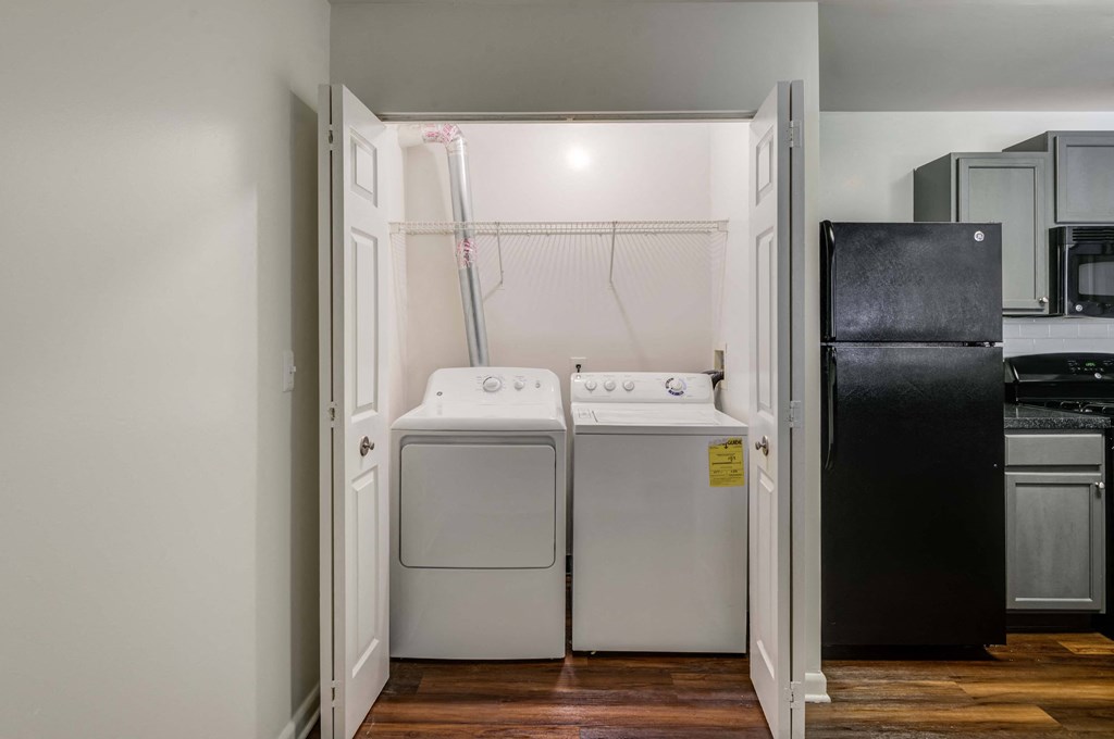 a washer and dryer in a laundry room with a black refrigerator