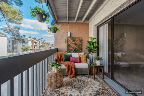 A balcony with a sofa, pillows, and plants.