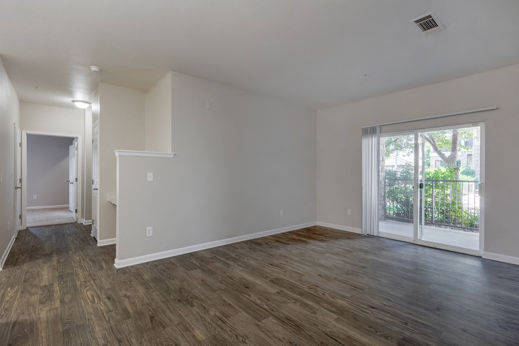 an empty living room with white walls and a sliding glass door