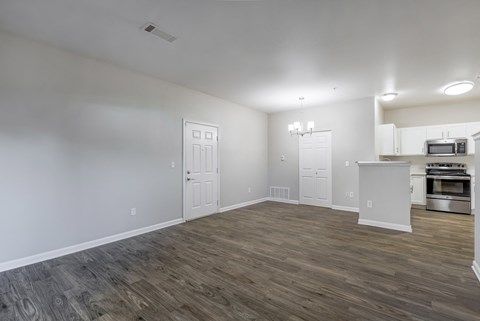 the living room and kitchen of an apartment with wood flooring
